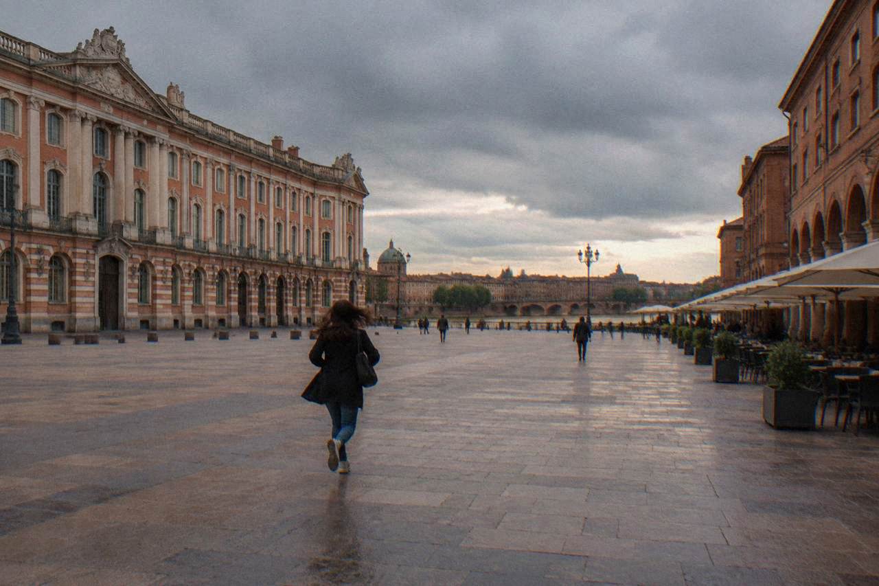 Rain clouds passing over the pink brick rooftops of Toulouse with the Garonne river below