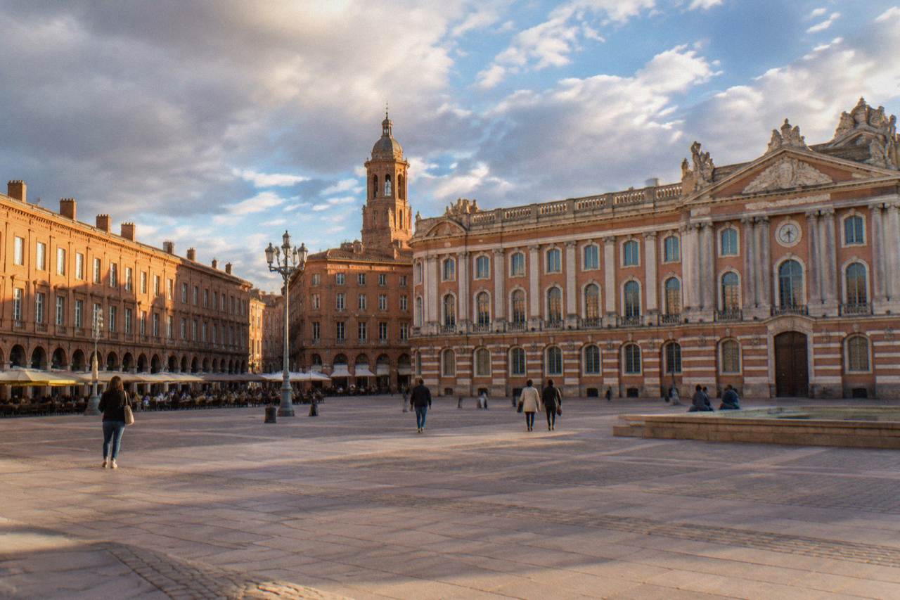 The pink brick facade and tower of the Capitole building in Toulouse seen from the square in front of it