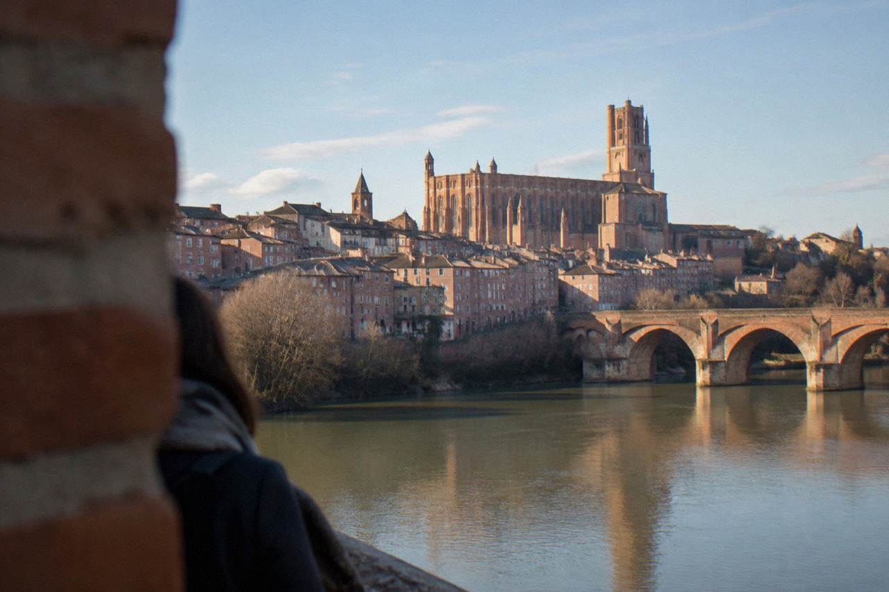 The red brick cathedral and old houses of Albi seen across the Tarn river