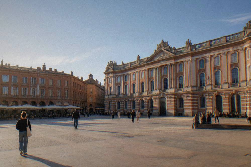 A visitor reading a sign at the entrance of a Toulouse museum while staff speak at the desk