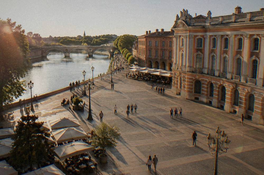 People strolling along the Garonne riverbank in Toulouse with the Pont Neuf in view