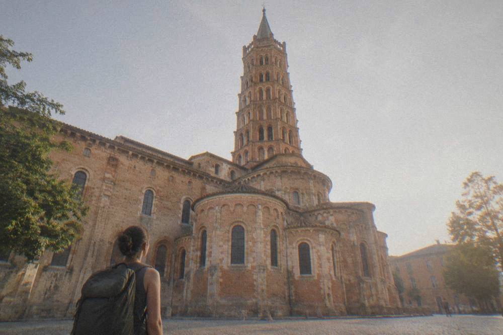 A solo traveller with a backpack looking at the Basilique Saint-Sernin in Toulouse
