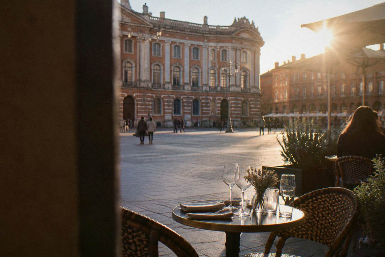 An elegant restaurant table set for dinner near the pink brick facades of Toulouse