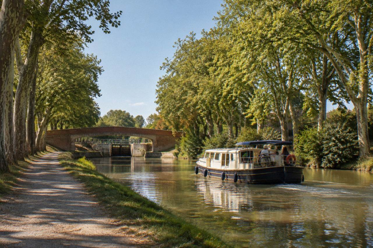 A canal boat gliding along the tree-lined Canal du Midi near Toulouse