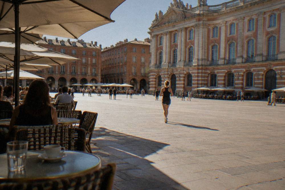 A shaded café terrace on a Toulouse square on a warm afternoon