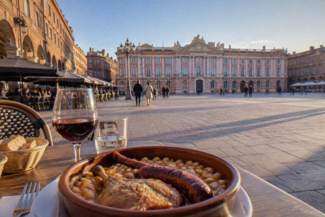 A traditional cassoulet served in a clay dish with beans, sausage and confit on a restaurant table