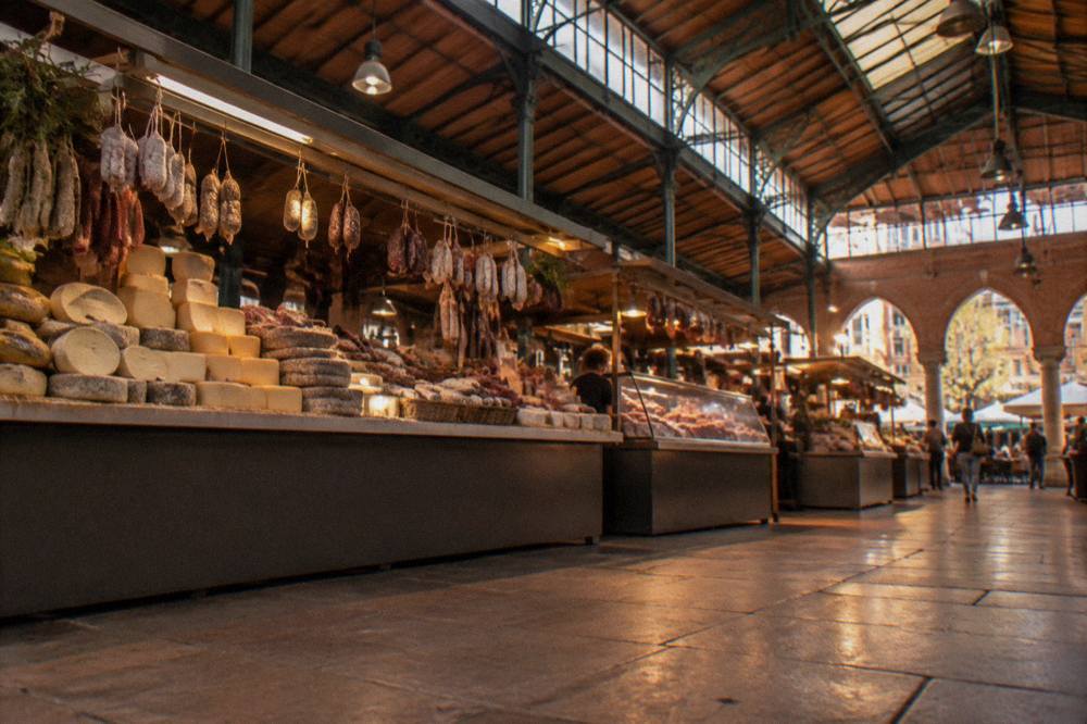 A covered market hall with cheese and charcuterie stalls in Toulouse