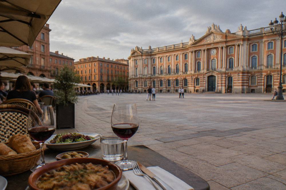 A table with wine glasses, bread, and regional dishes during an evening meal in Toulouse