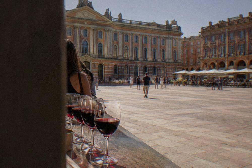 Glasses of red wine lined up on a wine bar counter in Toulouse