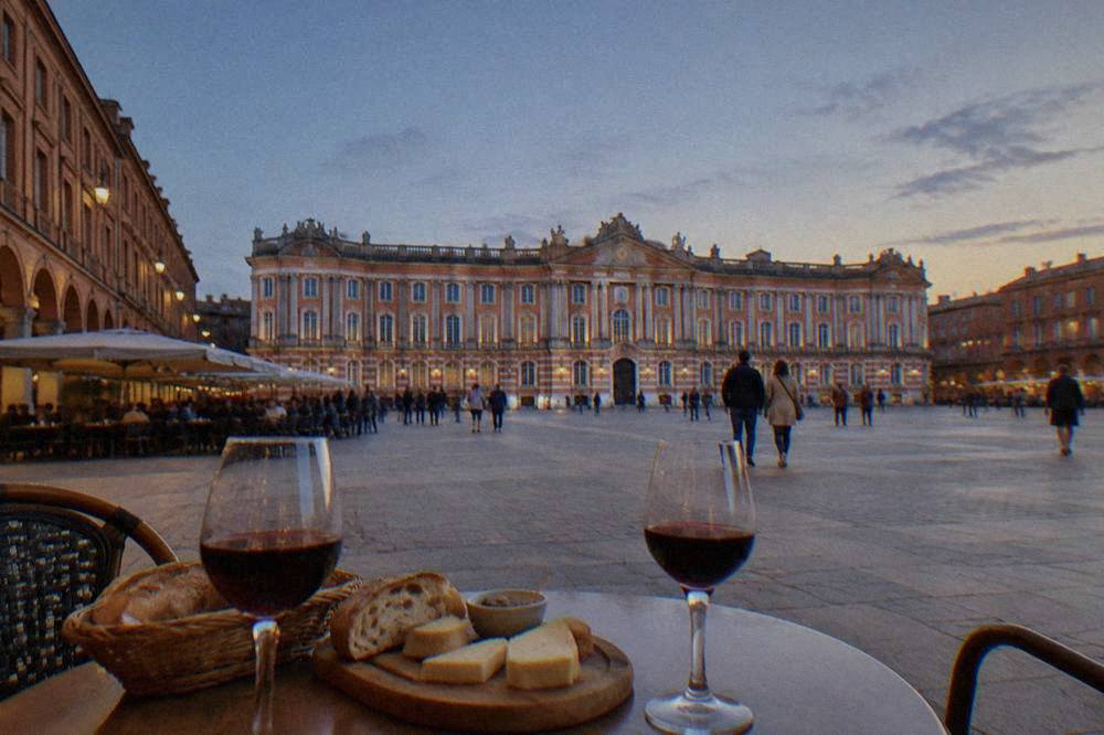 A table with bread, cheese and glasses of red wine at a Toulouse market bar