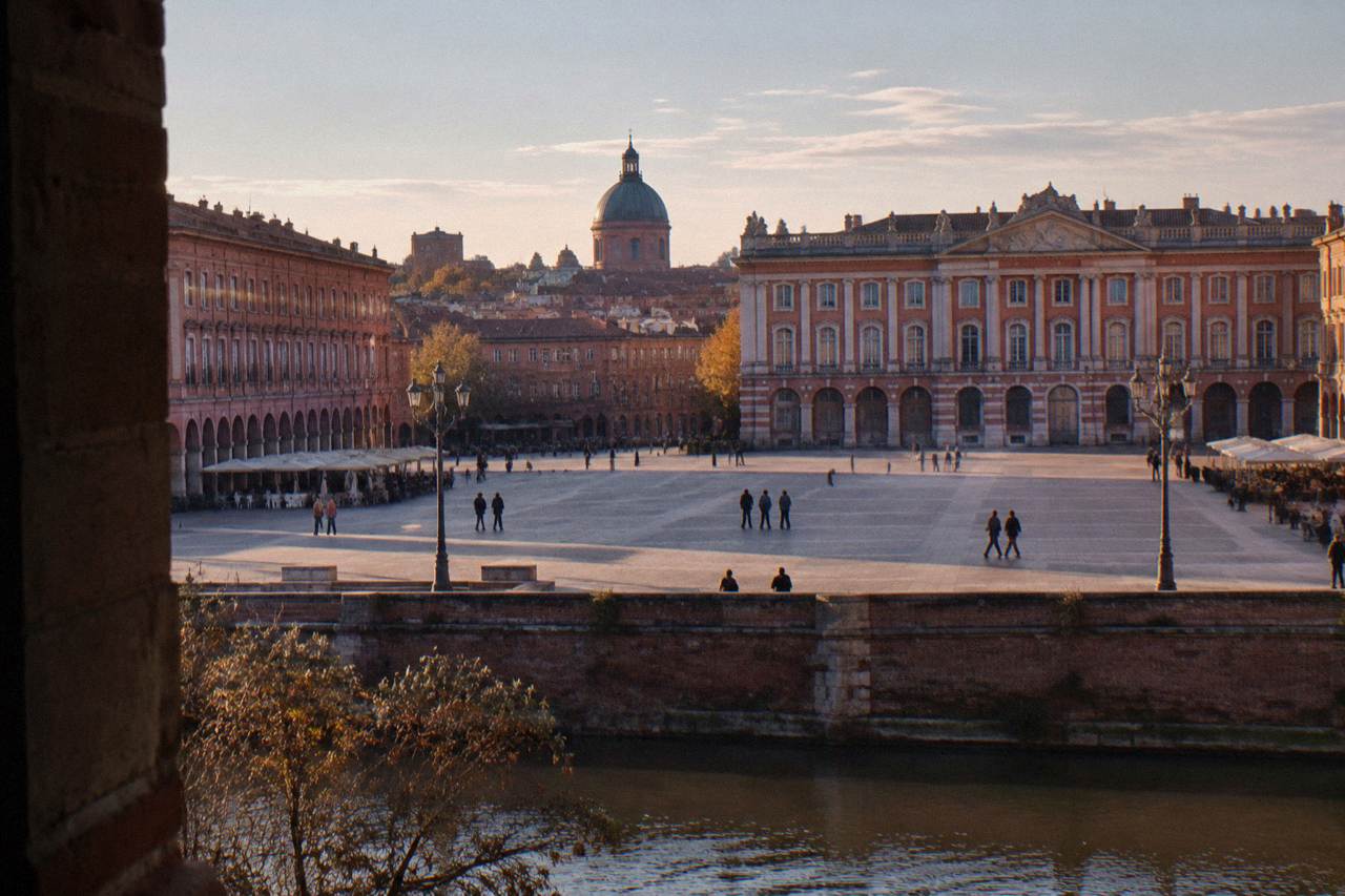Evening view over Toulouse rooftops with pink brick buildings and the dome of a church in the distance