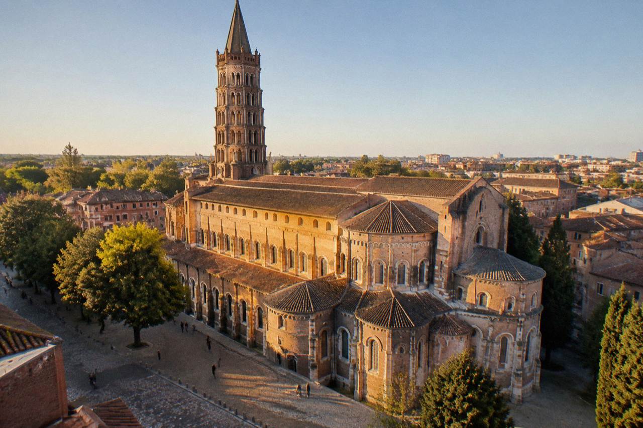 The tall stone bell Tower of the Basilique Saint-Sernin rising above the rooftops of Toulouse