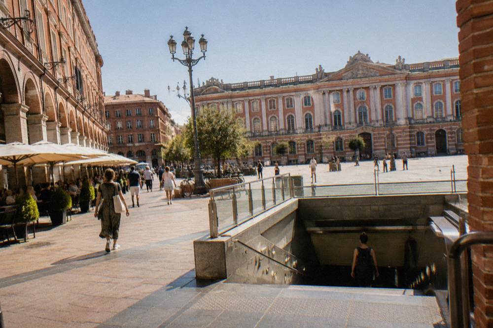 A street in Toulouse with a metro entrance and pedestrians