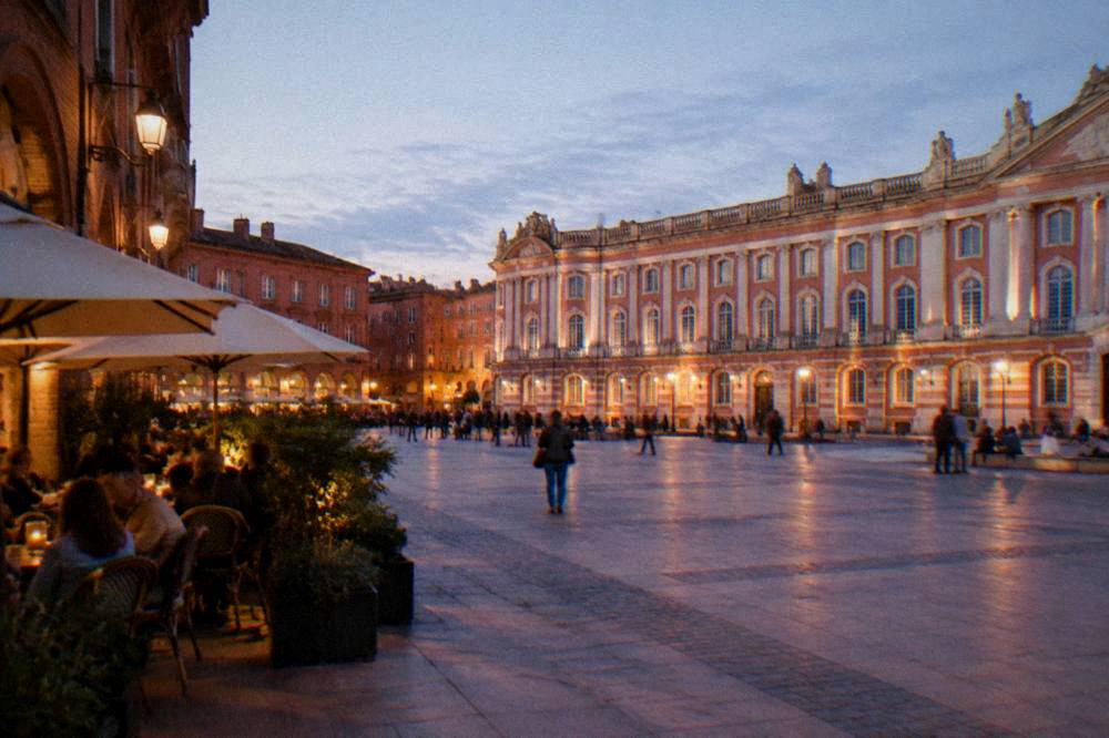 Evening light on pink brick facades and a cafe terrace in a Toulouse side street