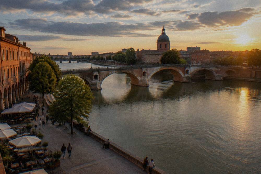 A bridge over the Garonne river connecting the two banks of Toulouse at dusk