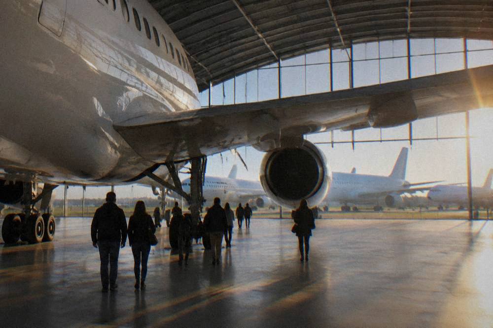 Visitors walking beneath the wing of a full-size airliner inside a bright museum hangar