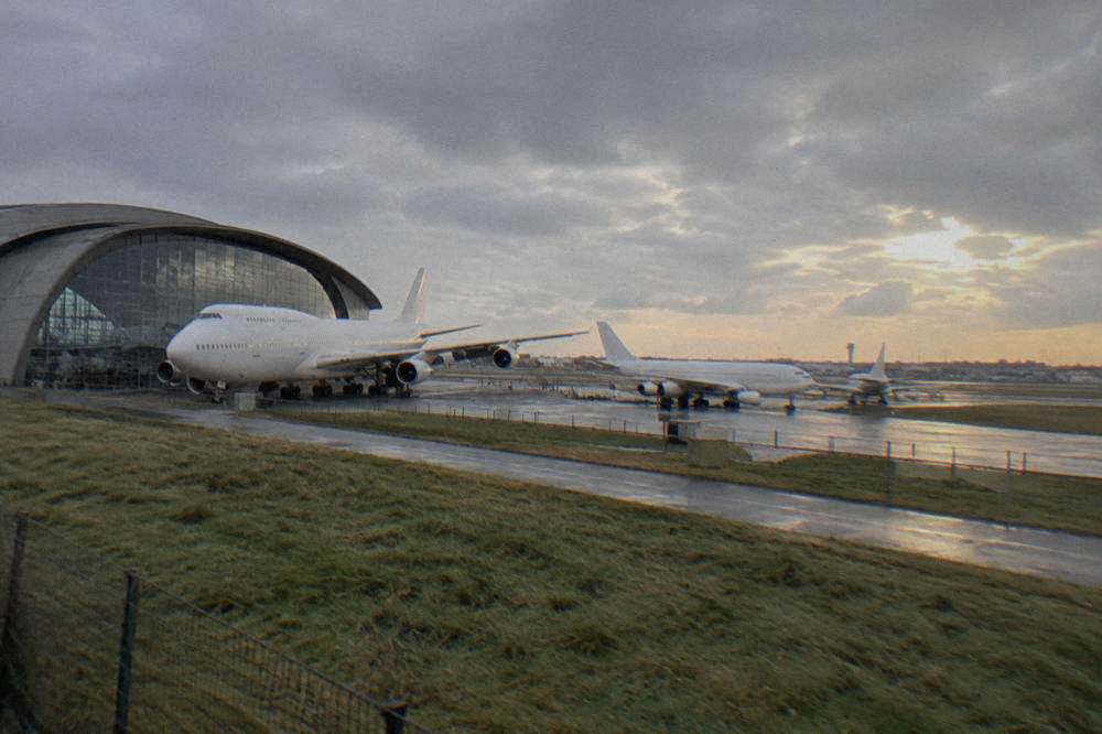 A wide view of airliners parked outside a museum building near an airport runway