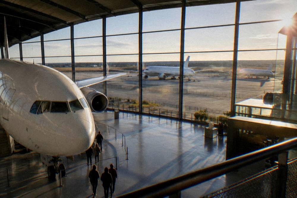 Morning light entering a large aircraft museum hall with visitors near an airplane nose