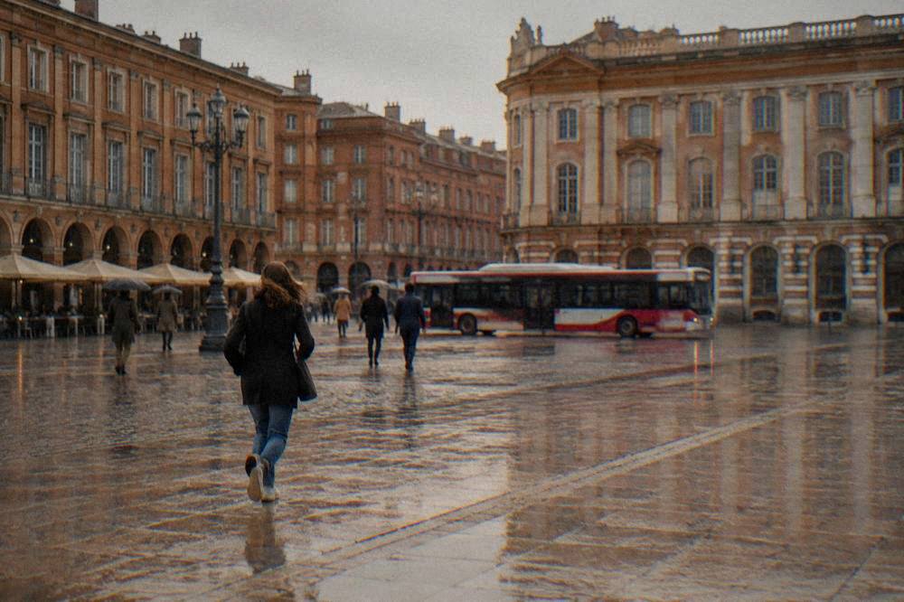 A red-and-white city bus passing pink brick buildings in central Toulouse