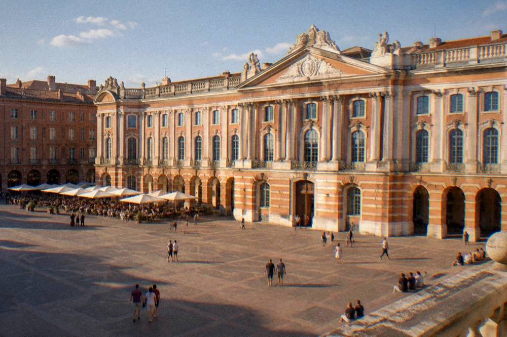 People sitting at outdoor cafe tables under the arcades beside the square on a warm evening