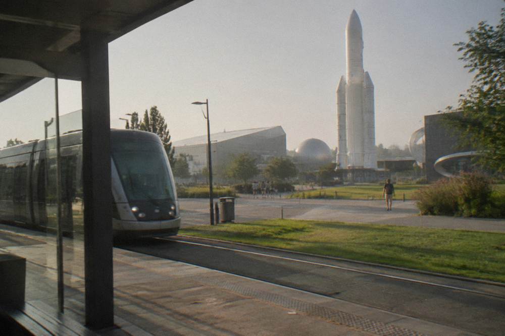 A modern tram passing a station platform in a French city