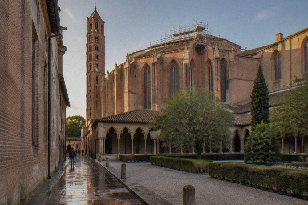 Scaffolding on the roof of a large brick Gothic church seen from a narrow street