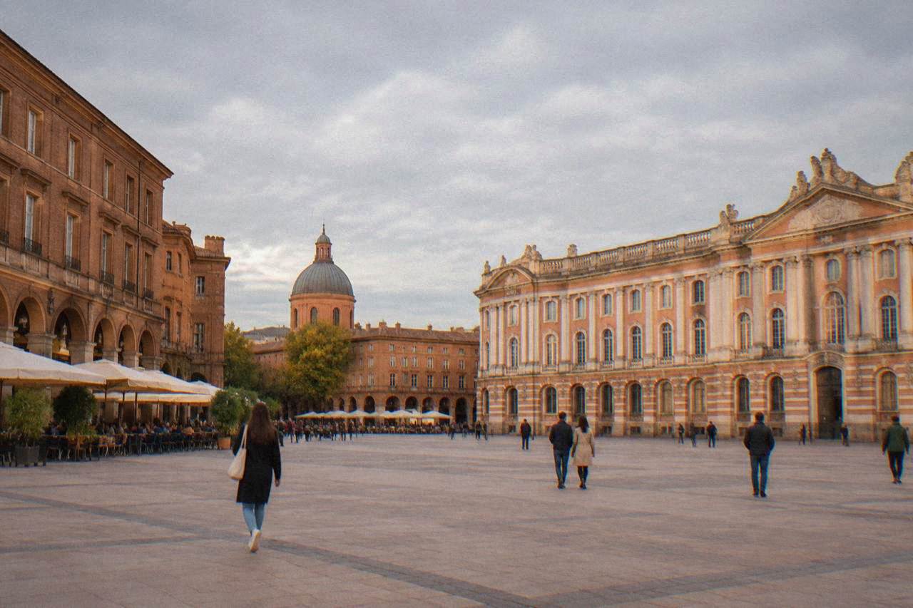 A pink brick dome with a lantern rising above rooftops beside the Garonne river in Toulouse