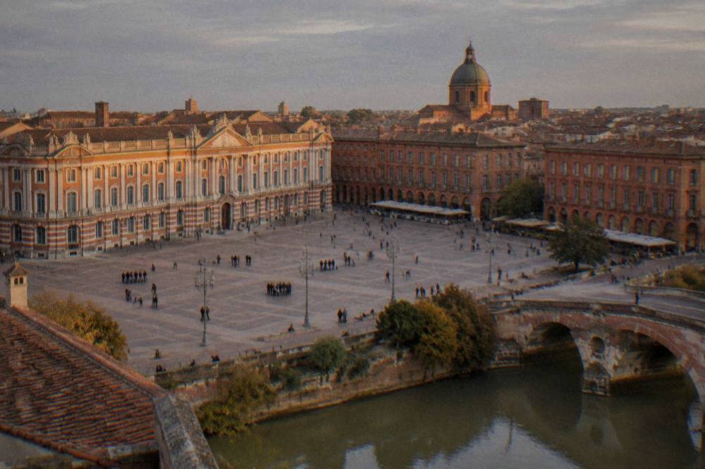The dome at dusk with warm light on the pink brick above the rooftops of Toulouse