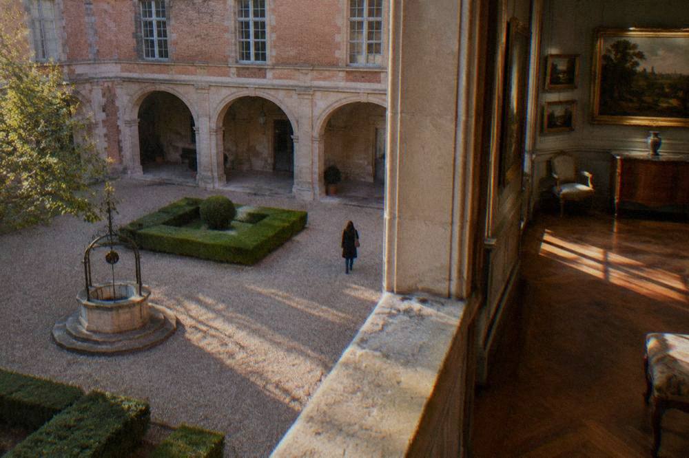 A gallery inside the Fondation Bemberg with oil paintings hung on paneled walls and period furniture