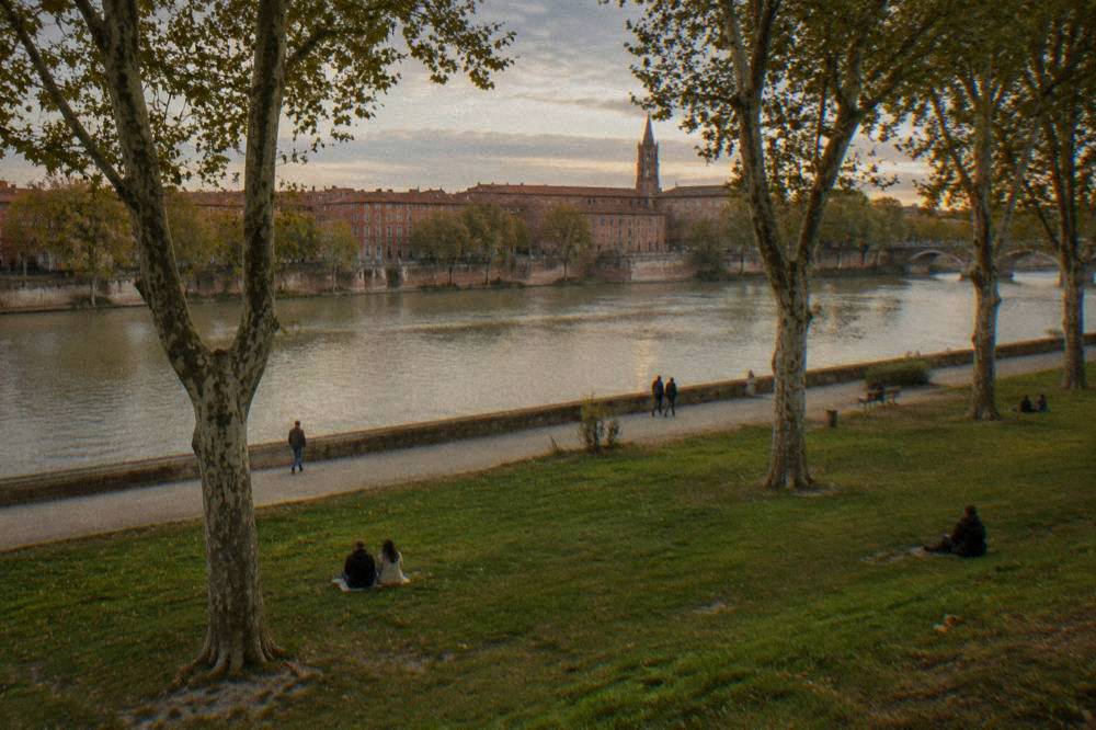 Pink brick buildings and a church tower seen from a Garonne riverside quay in Toulouse