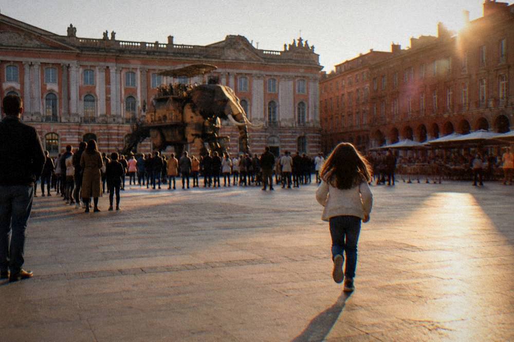A large mechanical machine on a square near Toulouse with spectators watching