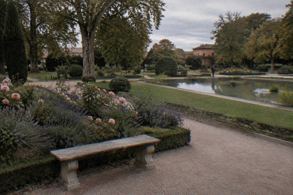 Stone bench beside a bed of lavender and roses in a formal garden