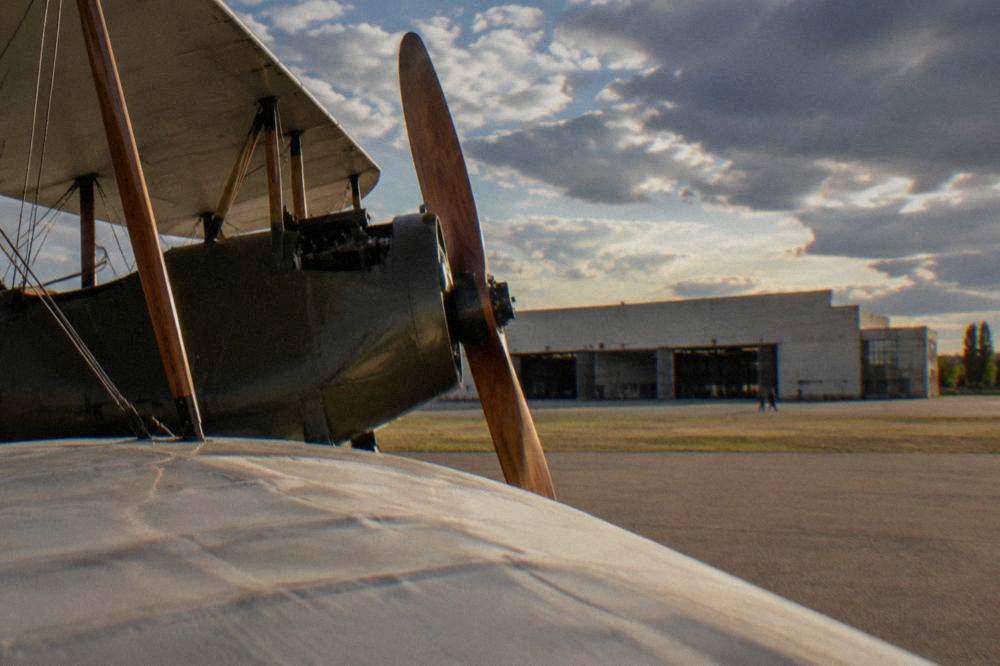 Close view of a restored biplane wing and wooden propeller in a museum display