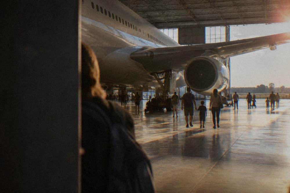 Families walking beneath the fuselage of a full-size airliner inside a large aircraft museum hangar
