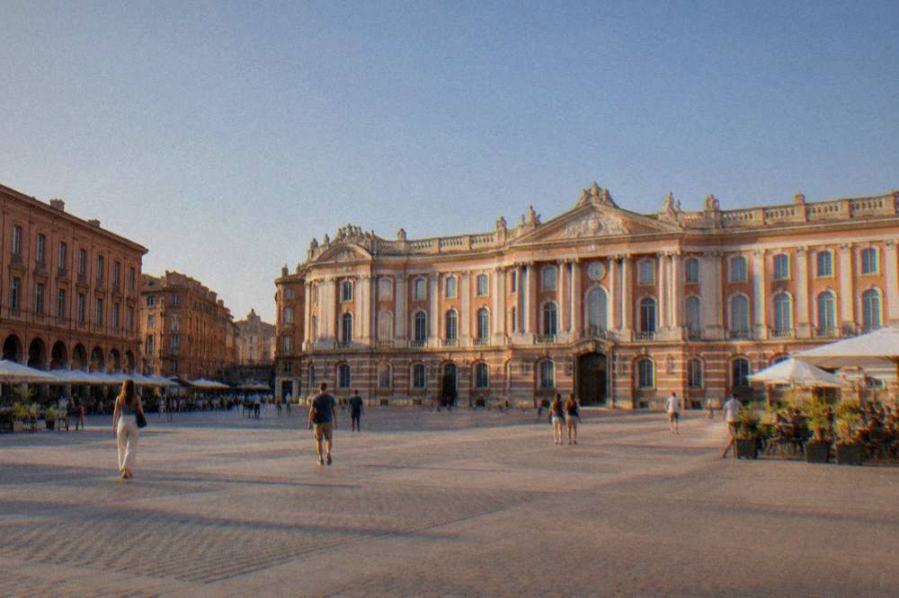 Pink brick facade of a historic Toulouse building glowing in late afternoon light