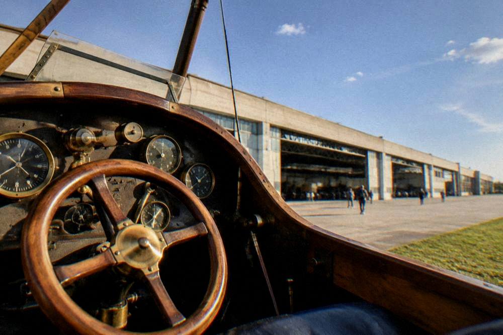 A vintage cockpit interior with brass instruments and a wooden control wheel on display