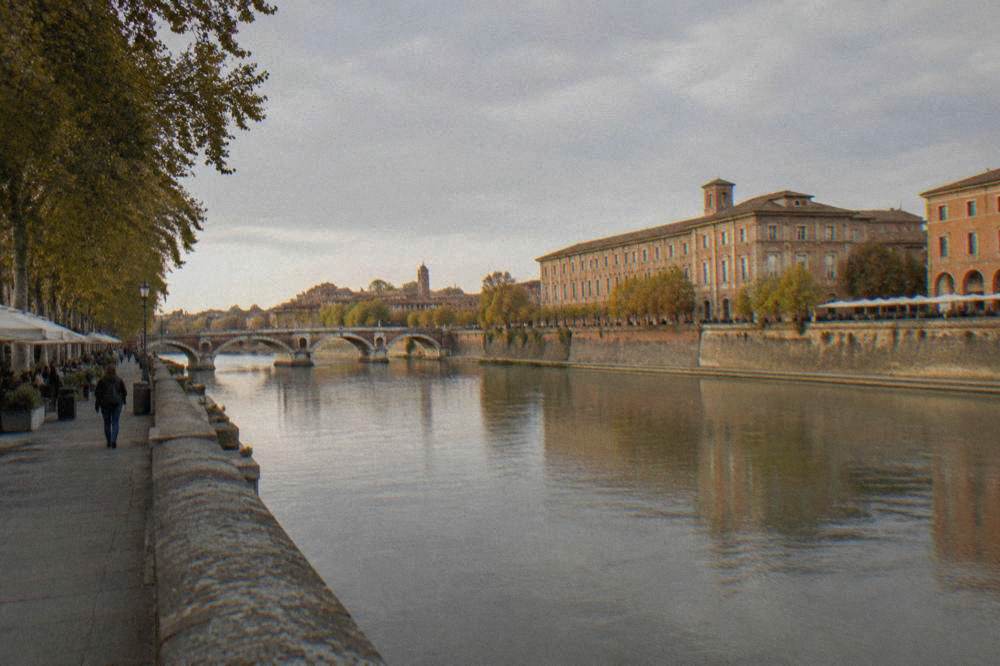 The Garonne river in Toulouse in late afternoon light, with the water reflecting the sky between the banks