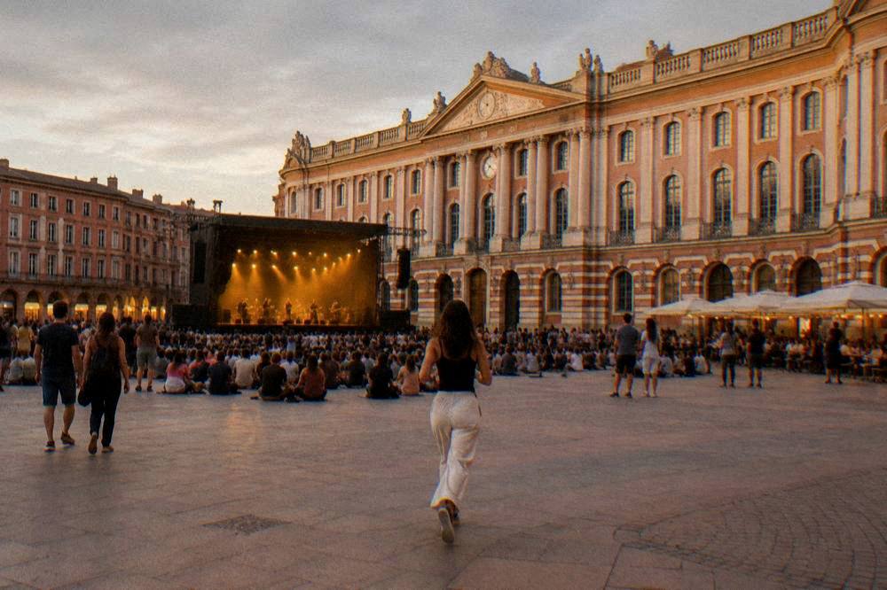 An evening concert crowd in a Toulouse venue with warm lighting over the audience