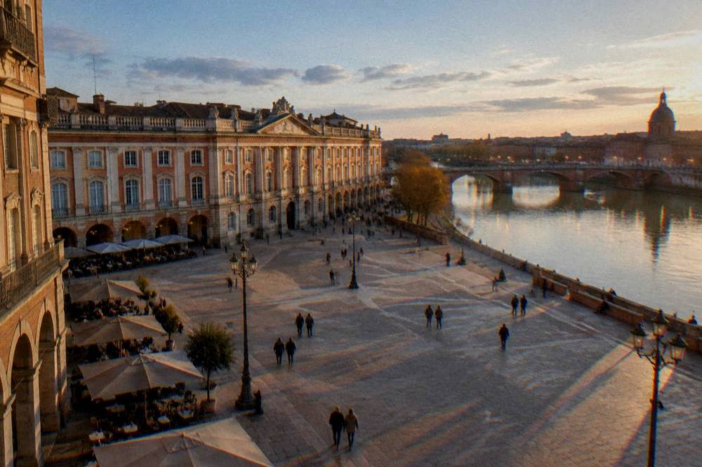 The Garonne riverbank in Toulouse at dusk, with the lights of the bridges reflecting on the water