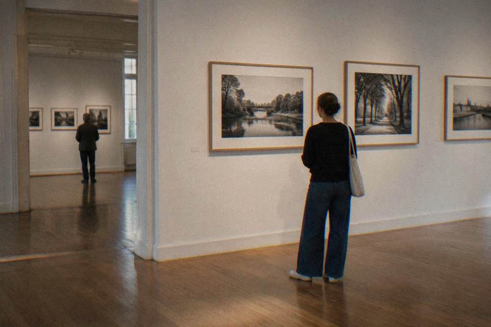 A gallery interior with framed photographs hung on a white wall and wooden floors