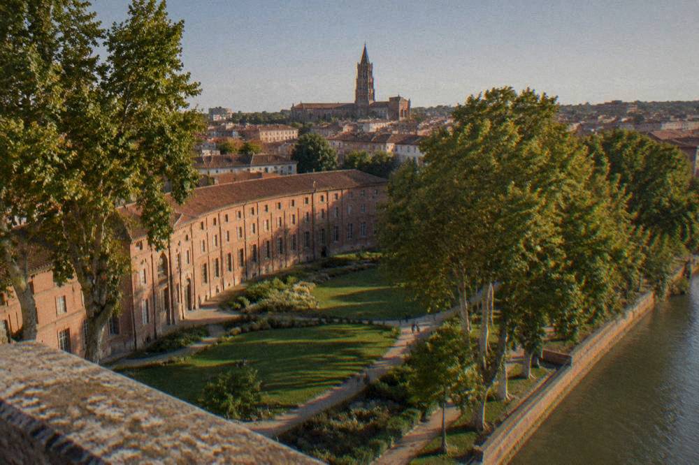A stone basilica tower rising above red tile rooftops in the late afternoon