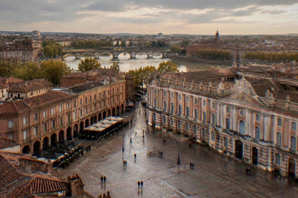 A high view across the pink-brick rooftops of central Toulouse toward the Garonne