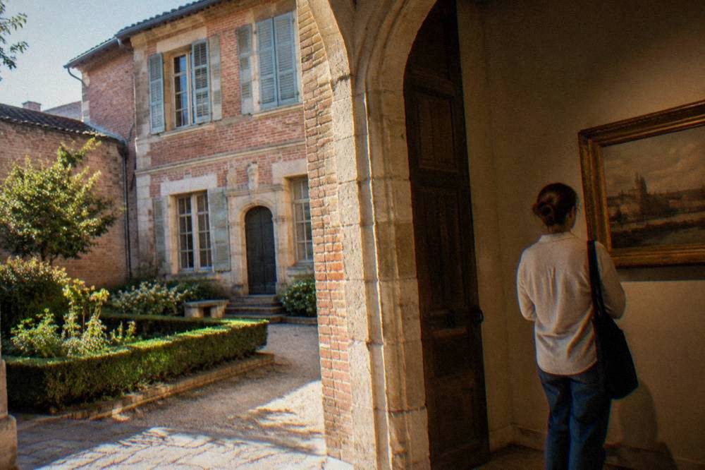 A visitor looking at framed old maps and photographs of a southern French city on a museum wall