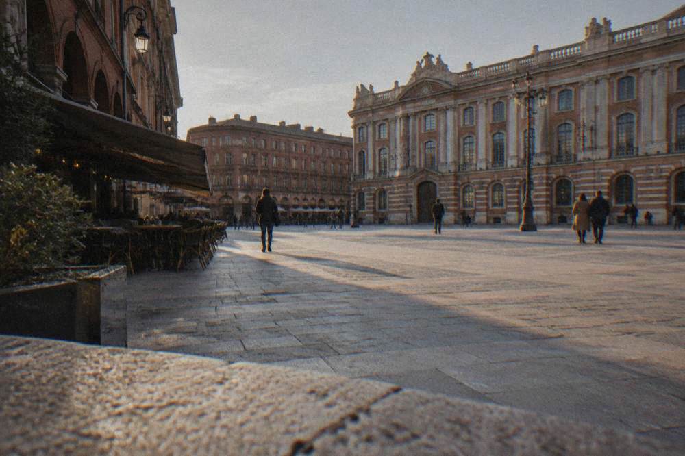A quiet old-town street in Toulouse with rose-colored brick walls and a cafe awning