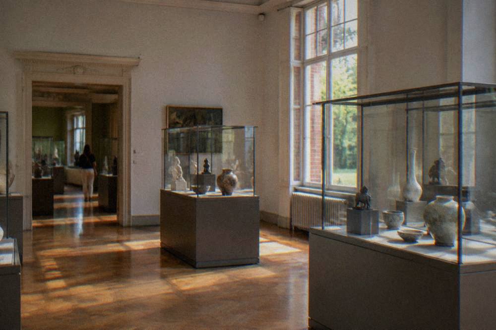 An interior gallery with glass display cases holding ceramics and small sculptures