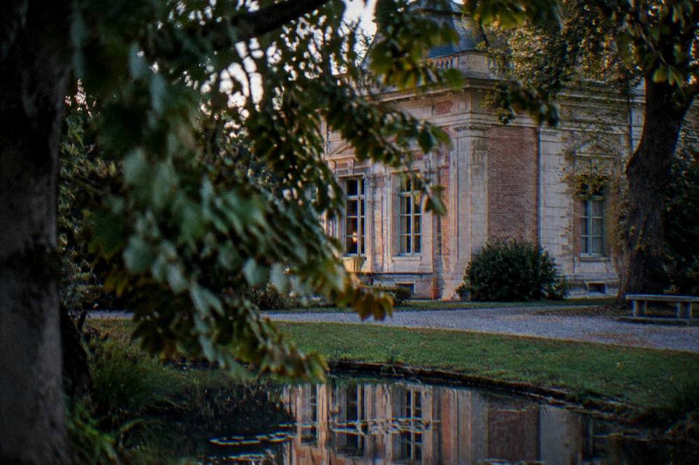 A quiet brick pavilion facade seen through tree branches in late afternoon light