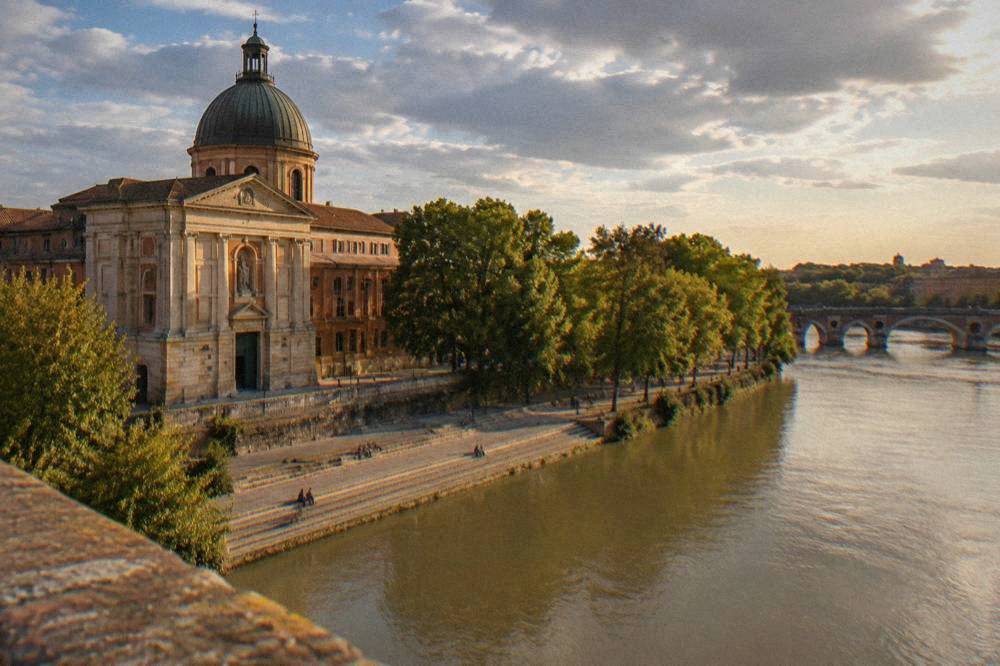 The Garonne river flowing past the quay in front of Notre Dame de la Daurade in Toulouse