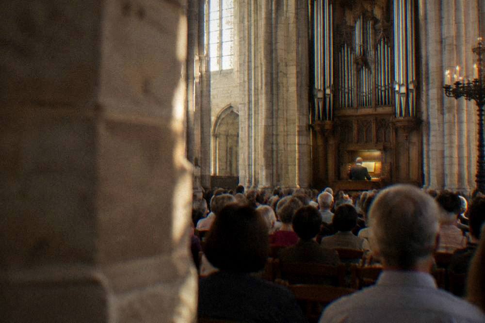 A concert audience inside a stone church in Toulouse during an organ festival