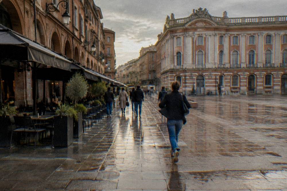 People walking along Rue du Taur past small shops in Toulouse