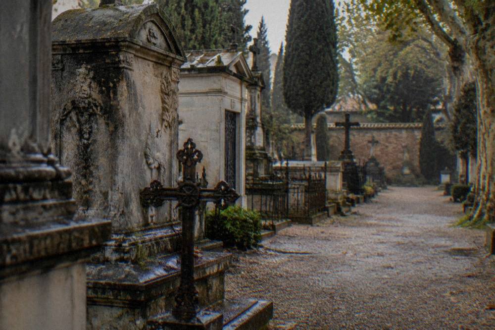 Close view of weathered stone tomb monuments with carved names and iron crosses